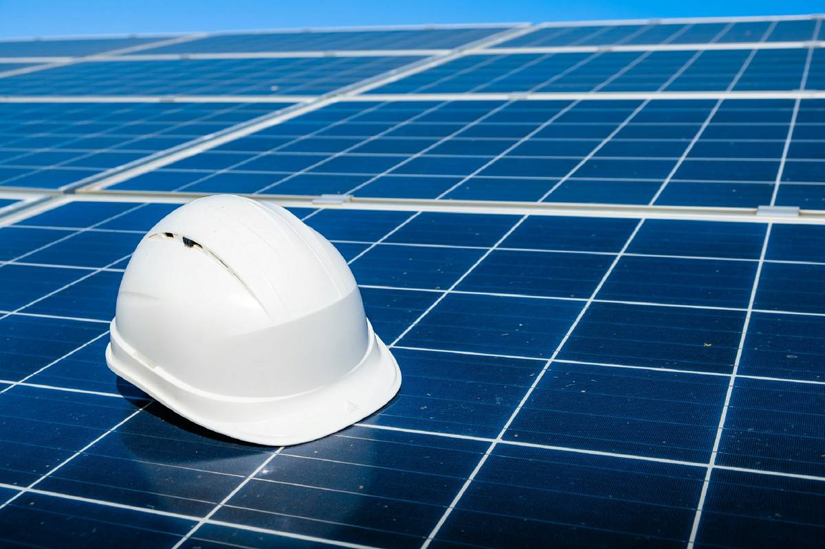 Damaged rooftop solar panels after a hailstorm with solar panel insurance policy documentation nearby
