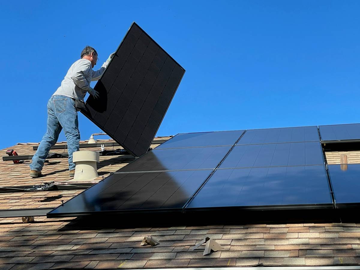 Close-up of hail-damaged solar panels with a technician holding a document titled solar power insurance policy